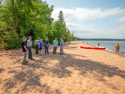 Friends board members talk with NPS Director Chuck Sams on Meyers Beach with red kayak in the background- NPS photo